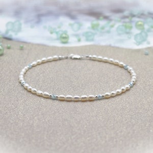 May include: A delicate white pearl and light blue gemstone bracelet with a silver clasp.