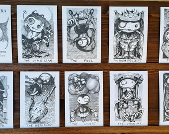 May include: A set of ten black and white tarot cards titled Bambolanera Tarot, featuring stylized illustrations of characters and symbols. The cards include The Magician, The Fool, The High Priestess, The Empress, The Emperor, The Hierophant, The Lovers, The Chariot, and Justice.