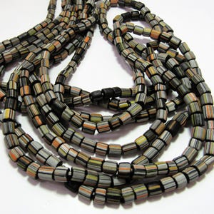 May include: A strand of multi-colored glass beads with black accents. The beads are cylindrical and have a striped pattern. The beads are strung on a black cord.