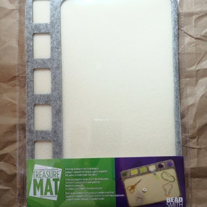 May include: Gray felt beading mat with seven compartments and a white felt surface. The mat is labeled "seed bead TREASURE MAT" and measures 11 x 8.5 inches (27.9 x 20.3 cm).