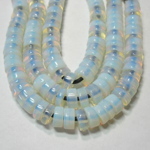 May include: A strand of white opal beads with iridescent shimmer. The beads are round and have a smooth, polished finish.
