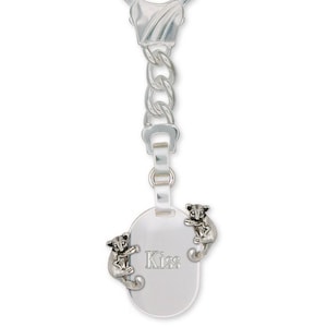 May include: Silver keychain with a silver oval charm that says "Kiss" and two silver animal figurines on either side of the charm.
