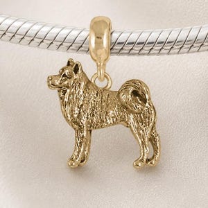 May include: A gold-toned charm shaped like a standing dog with a curled tail, suspended from a silver-toned snake chain. The charm features detailed fur texture and a small loop at the top for attachment. The text Chain sold separately is visible.