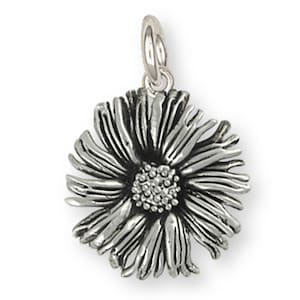 May include: A silver charm in the shape of a stylized daisy flower. The charm has a detailed design with a central circle of smaller circles.