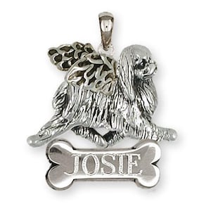 May include: Silver pendant featuring a Pekingese dog with wings and a bone charm engraved with the name "JOSIE".