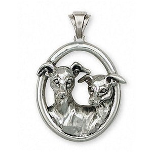 Puede incluir: Colgante de plata de ley con dos galgos italianos en un marco ovalado. Los perros están mirando hacia adelante con sus cabezas tocándose.
