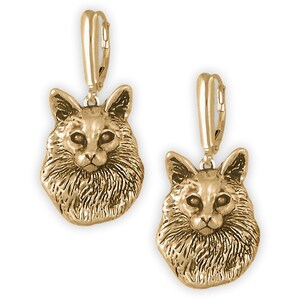 May include: Gold-tone dangle earrings featuring a detailed sculpted image of a long-haired cat's head.