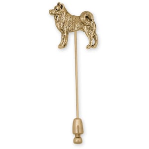 May include: A gold-colored lapel pin featuring a detailed Shiba Inu dog design. The pin has a long, slender stem with a decorative end. The dog is standing, with its tail curled over its back.