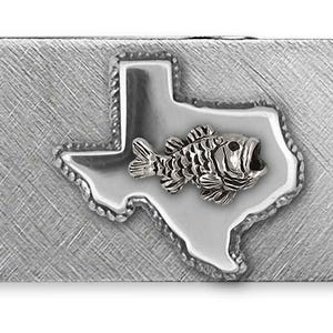 Puede incluir: Un clip para billetes plateado con un acabado texturizado. Presenta un contorno detallado del estado de Texas, con un emblema de pez en el centro. El clip es rectangular y está diseñado para sujetar billetes doblados.