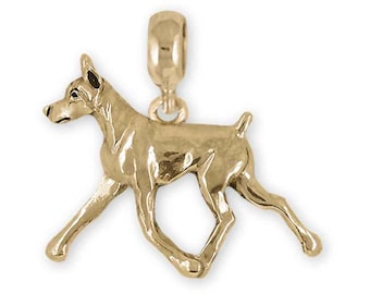 May include: A gold-toned charm of a Doberman Pinscher dog in a walking pose.