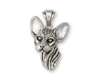 Puede incluir: Un colgante de plata con una escultura tridimensional detallada de la cabeza de un gato Sphynx.