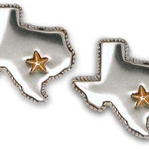 Puede incluir: Un par de pendientes de plata con forma del estado de Texas con una estrella dorada en el centro de cada pendiente.