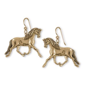 May include: A pair of gold-colored earrings shaped like running horses. The earrings have a detailed design, with flowing manes and tails. The hooks are simple and gold-toned.