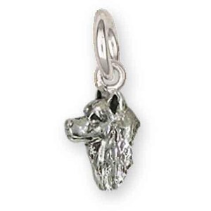 May include: A silver-colored charm in the shape of a dog's head, featuring detailed facial features and a loop for attaching to a necklace or bracelet. The charm is small and appears to be made of metal.