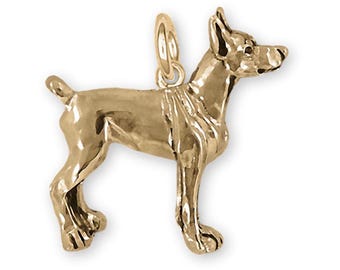 May include: A gold-colored charm of a Doberman Pinscher dog. The charm is standing on all four legs with its head turned to the right. The charm is made of metal and has a shiny finish.