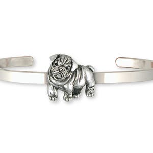 Puede incluir: Una pulsera de plata con un pequeño encanto de pug detallado. La pulsera es una banda simple y delgada con un cierre de bisagra.