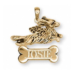 May include: Gold-tone pendant featuring a dog with wings, flying over a bone-shaped tag with the name "JOSIE" engraved on it.
