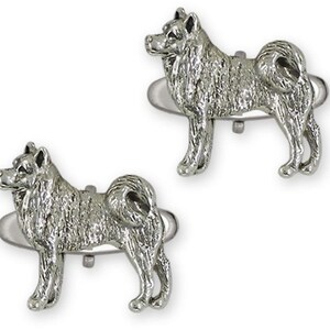 May include: Two silver-colored dog-shaped cufflinks. The cufflinks are detailed with the features of the dog breed, including fur texture and curled tail. The dogs are standing on a silver bar.