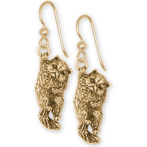 May include: A pair of gold-colored cat earrings. Each earring features a detailed, three-dimensional Persian cat design hanging from a simple hook. The cats have textured fur and are in a playful pose.