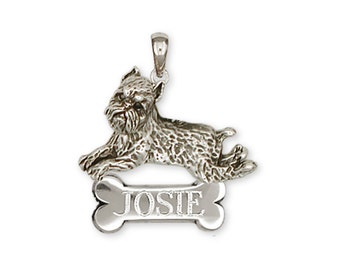 May include: A silver pendant featuring a detailed miniature Schnauzer dog lying down. Below the dog is a bone-shaped tag with the name "JOSIE" engraved on it. The pendant has a loop for a chain.