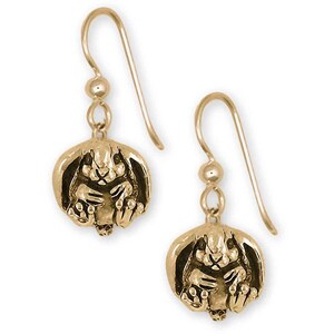 May include: A pair of gold-colored drop earrings. Each earring features a detailed bunny pendant with a textured surface. The bunny is in a seated position with its ears up. The earrings have a simple hook closure.