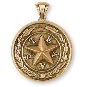 May include: Gold-tone pendant featuring the state seal of Texas. The seal depicts a five-pointed star surrounded by a laurel wreath and the word "TEXAS".