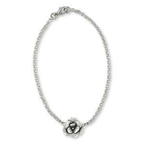 Könnte beinhalten: Ein silbernes Kettenarmband mit einem zarten silbernen Blumenanhänger.