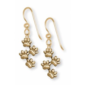 May include: Gold dangle earrings with a design of five paw prints hanging from the bottom of each earring.