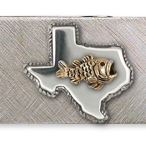 Puede incluir: Un clip de dinero plateado con un acabado texturizado. El clip presenta un emblema de pez dorado dentro de un contorno en forma de Texas. El pez tiene escamas detalladas y la boca abierta. El contorno de Texas está bordeado por un diseño plateado en forma de cuerda.