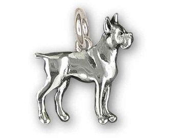 Puede incluir: Encanto de plata de un perro boxer de pie con la cabeza girada hacia un lado. El encanto es detallado y realista.