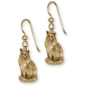 May include: Gold-tone dangle earrings featuring a detailed, sculpted image of a long-haired cat sitting with its tail curled around its legs.