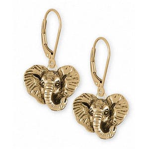 May include: A pair of gold-colored leverback earrings. Each earring features a detailed elephant head pendant. The elephant heads have textured skin and prominent tusks, with a leverback closure for secure wear.
