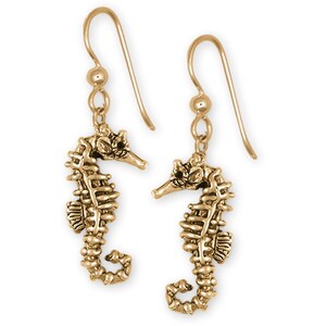 May include: Gold-tone dangle earrings featuring a detailed seahorse design. The earrings have a hook closure.