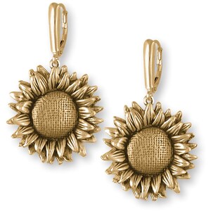 May include: A pair of gold-tone sunflower dangle earrings with a textured finish. The earrings have a leverback closure.