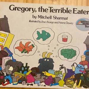 May include: A children's book cover with a colorful illustration of a goat eating various objects. The title of the book is "Gregory, the Terrible Eater" by Mitchell Sharmat. The book is illustrated by Jose Aruego and Ariane Dewey.