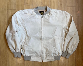 May include: A cream-coloured bomber jacket with a zip fastening and ribbed cuffs and waistband. The jacket has a small embroidered logo on the left chest.