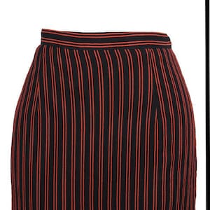 Op de afbeelding: Een zwarte rok met dunne rode verticale strepen. De rok is knielengte en heeft een rechte silhouet.