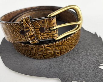 Könnte beinhalten: Ein brauner Ledergürtel mit Kroko-Muster und einer goldfarbenen Schnalle.