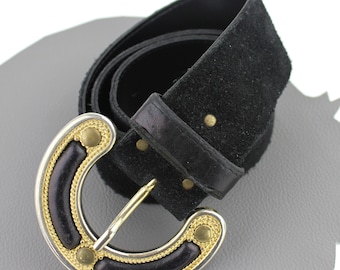 May include: A black suede belt with a silver and gold buckle. The buckle has a decorative design with gold accents and a black leather inlay.