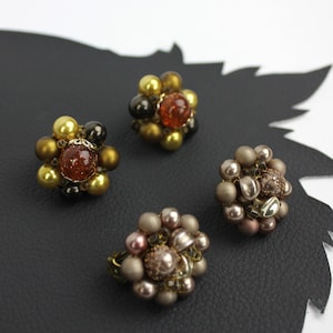 May include: Three pairs of flower-shaped earrings with a variety of colors and textures. The earrings are made of beads and have a vintage look.