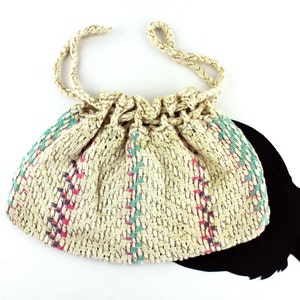 May include: A white crocheted drawstring bag with pink, blue, and gray stripes. The bag has a long, knotted drawstring.