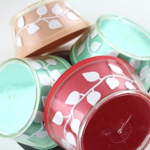May include: Four vintage plastic bowls with a white leaf design. The bowls are in shades of pink, red, and green.