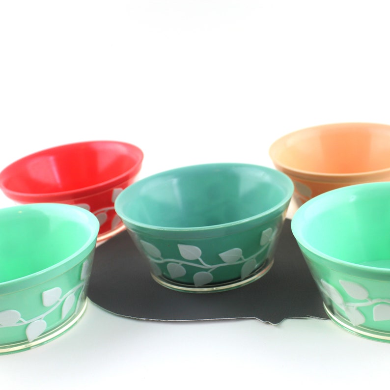 May include: Five vintage bowls with a leafy design. The bowls are in shades of green, red, and orange.
