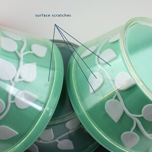 May include: Set of three green plastic bowls with white leaf designs. The bowls have surface scratches.