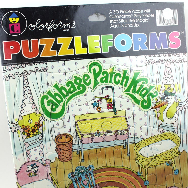Puede incluir: Un rompecabezas Colorforms de 30 piezas que representa una escena de guarder&iacute;a de Cabbage Patch Kids. El rompecabezas incluye una cuna, una mesa para cambiar pa&ntilde;ales, una mecedora y una cig&uuml;e&ntilde;a con un beb&eacute;. Las piezas del rompecabezas est&aacute;n hechas de pl&aacute;stico de colores y se pegan como por arte de magia.