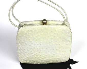 May include: A white ostrich leather handbag with a gold clasp and double handles.