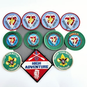 May include: A collection of ten embroidered patches featuring the Boy Scouts of America logo, including a diamond jubilee patch, a family camper patch, a high adventure patch, and a troop committee chairman patch.