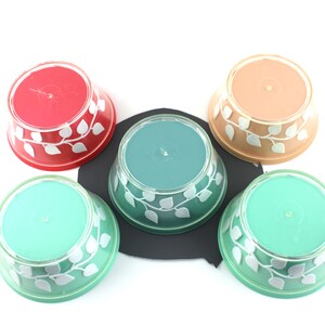 May include: Five small bowls with a white leaf design. The bowls are in shades of red, orange, teal, and green.