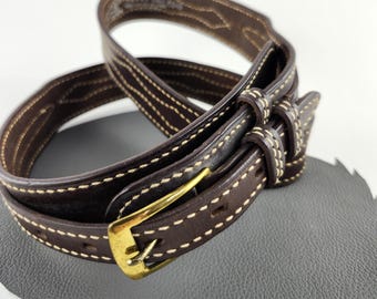 May include: A brown leather belt with a gold buckle and white stitching. The belt is folded in half and the buckle is visible.
