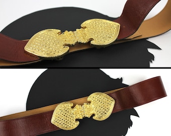 May include: A brown leather belt with a gold-toned, ornate, double-heart buckle.